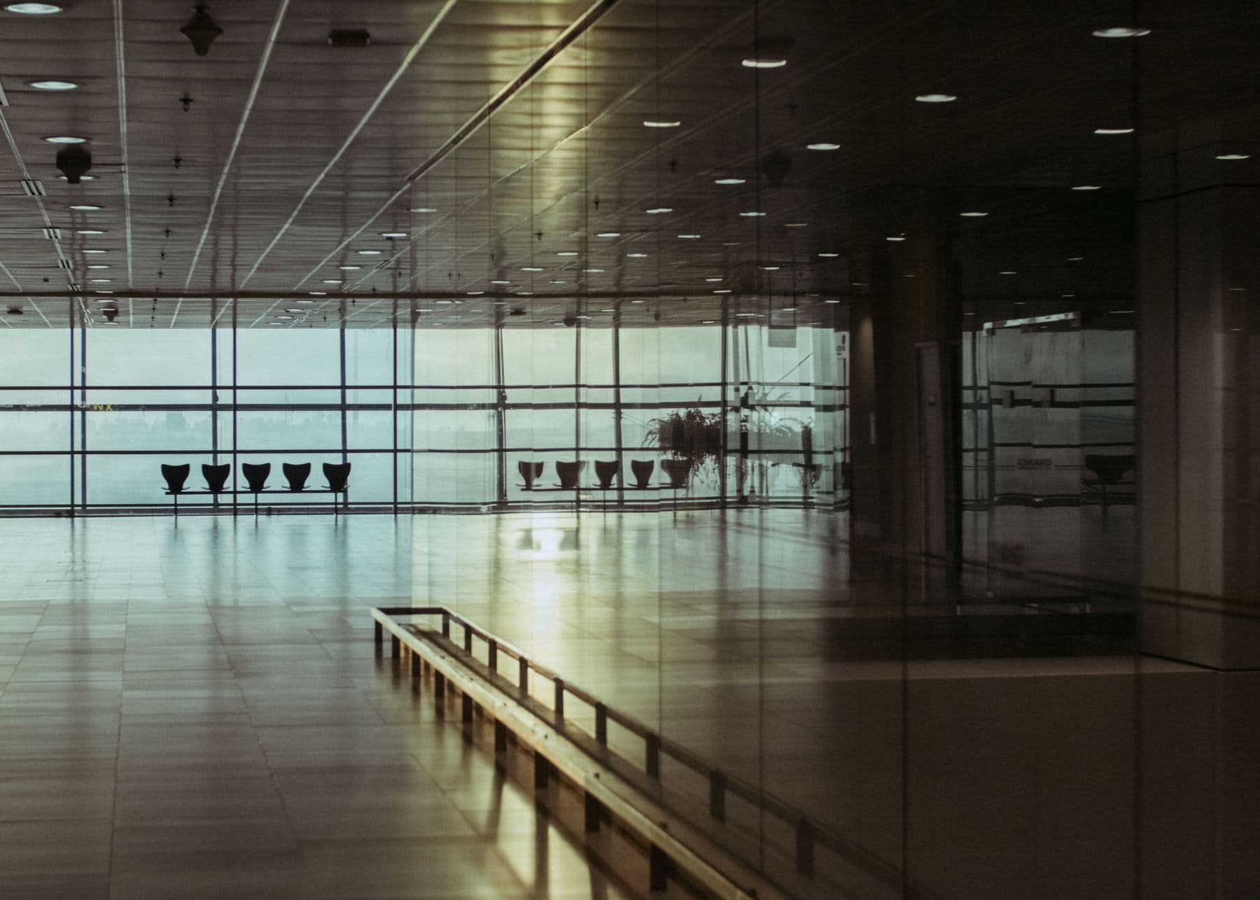 An empty airport terminal in Singapore with a polished floor and a glass wall.