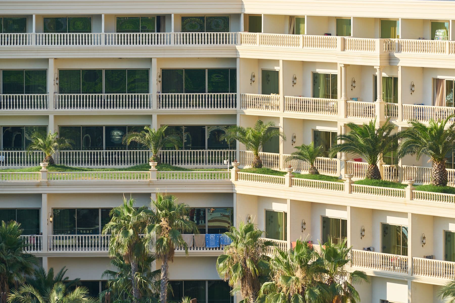 A cream resort building with white balcony railings and palm trees.